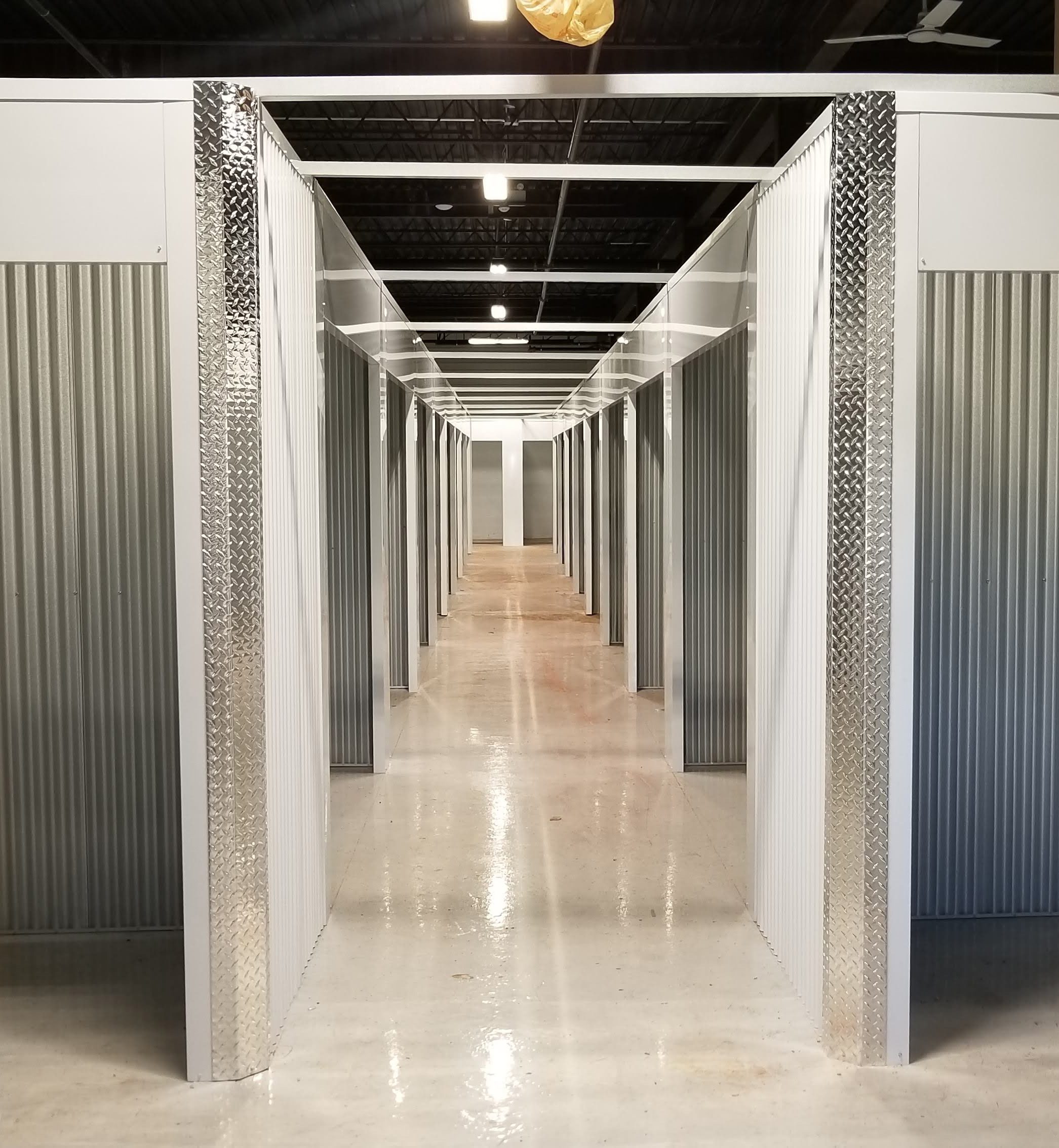 Interior self-storage hallway with corrugated locker partitions and polished concrete floor