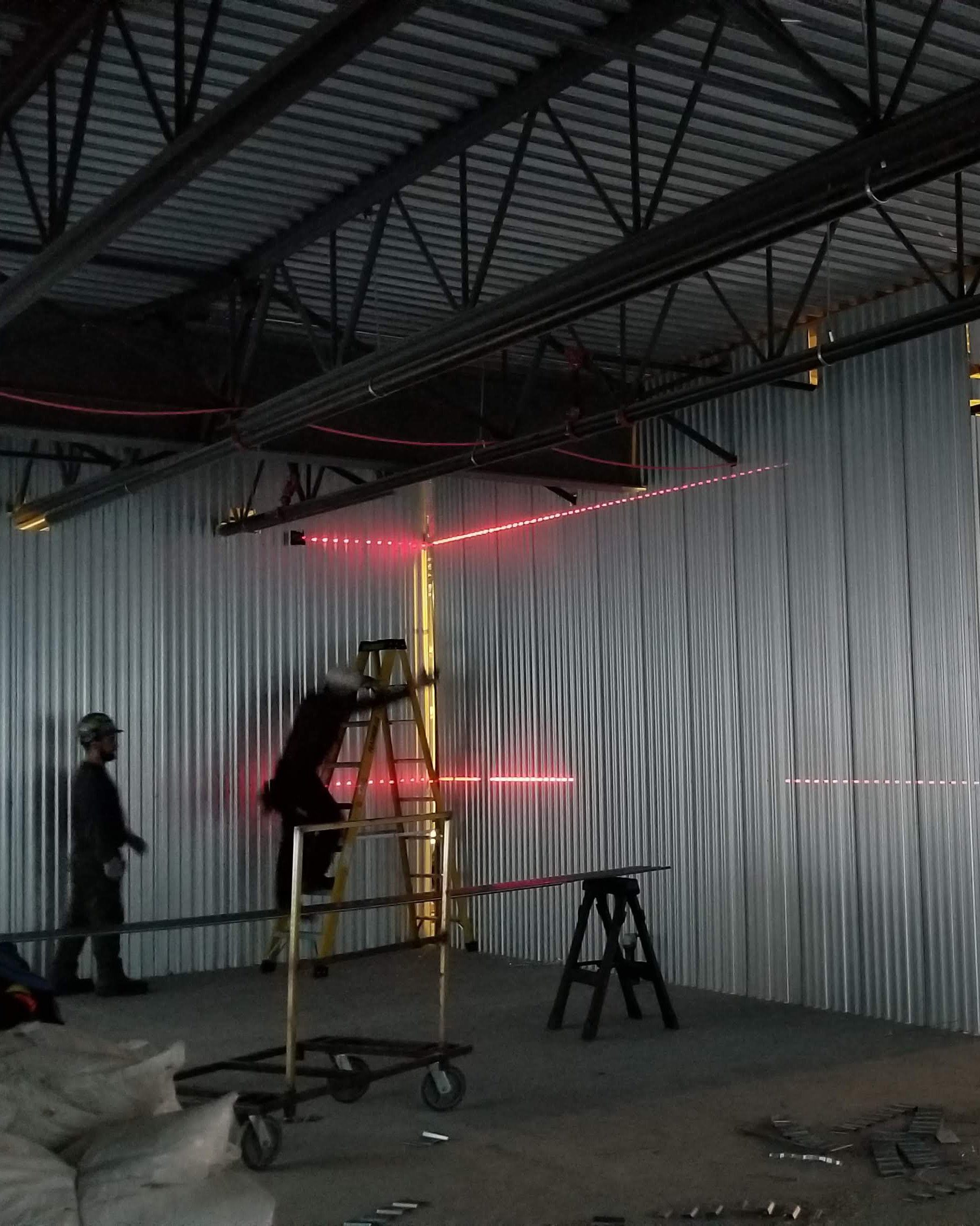 Technician using a laser level to align a self-storage partition during a facility repair